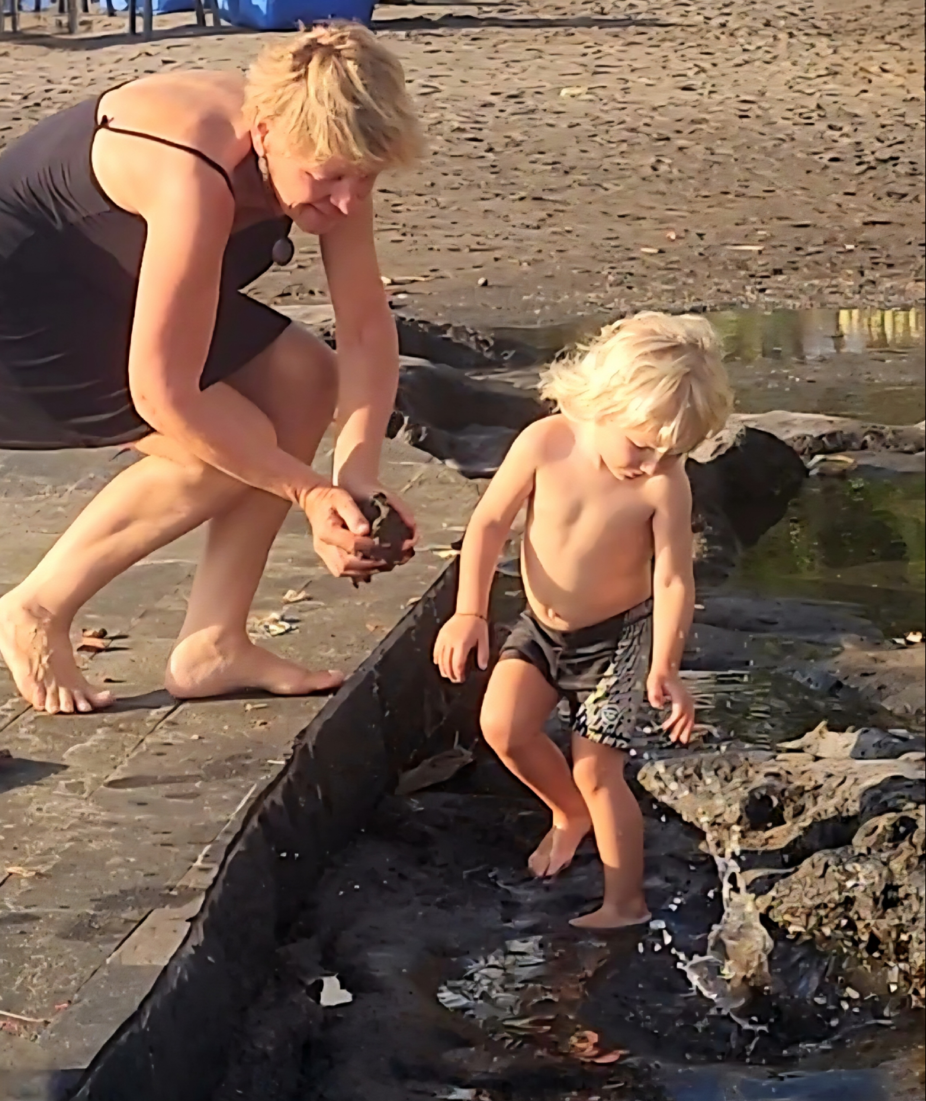 Child playing in water with an adult nearby